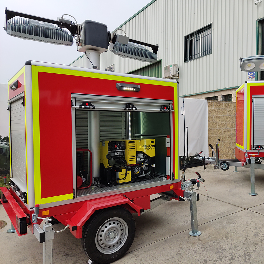 Remorque rouge avec rideaux métalliques, dont l’un est ouvert pour montrer un générateur et des équipements, surmontée d’un mât avec deux projecteurs.<br />
